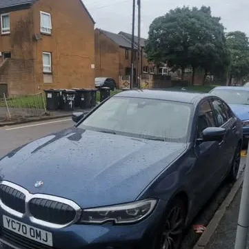 Blue BMW 3 Series parked on a residential street